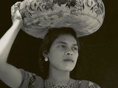 a woman carrying a large vase on her head