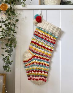 a crocheted christmas stocking hanging on a wall next to a potted plant