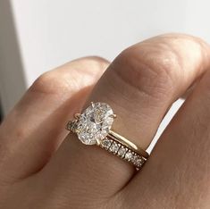 a woman's hand with a diamond ring on top of her finger and an engagement band