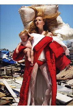 a woman holding a baby in her arms while standing next to a pile of junk