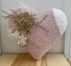 a pink heart shaped pillow sitting on top of a wooden table next to a white wall