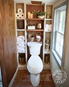 a white toilet sitting inside of a bathroom next to a wooden shelf filled with towels