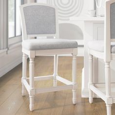 two white chairs sitting next to each other on top of a hard wood floored floor