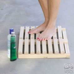 a woman standing on top of a wooden pallet next to a bottle