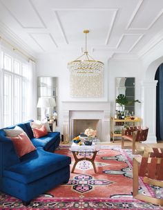 a living room filled with furniture and a fire place under a chandelier above a fireplace