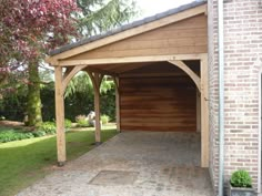 a wooden carport in front of a brick building with an open garage door on the side