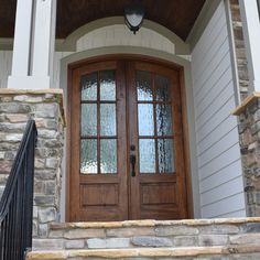 the front door of a house with two glass doors and stone steps leading up to it