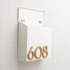 a white wall mounted mailbox with the number sixty8 on it