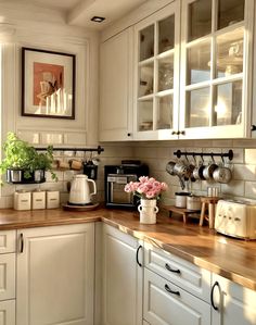 a kitchen with white cabinets and wooden counter tops, flowers in vases on the counter