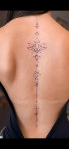 the back of a woman's neck with a flower tattoo on her lower back