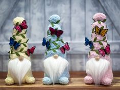 three small stuffed animals sitting next to each other on a wooden table with butterfly decorations