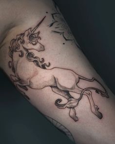 a black and white photo of a unicorn tattoo on the left upper half of the arm