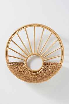 a wicker basket with a circular handle on the front and bottom, hanging from a wall