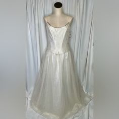 a white wedding dress on display in front of curtains