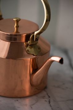 a copper tea pot on a marble table