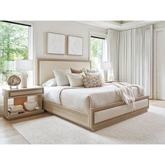 a large white bed sitting in a bedroom next to two nightstands and a window