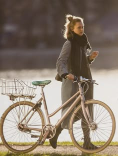 the woman is walking her bike by the water