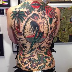 the back of a woman's body with tattoos on it