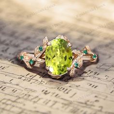 a ring with an oval green stone surrounded by emeralds on top of music sheets