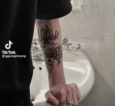 a man with a tattoo on his arm is standing in front of a bathroom sink