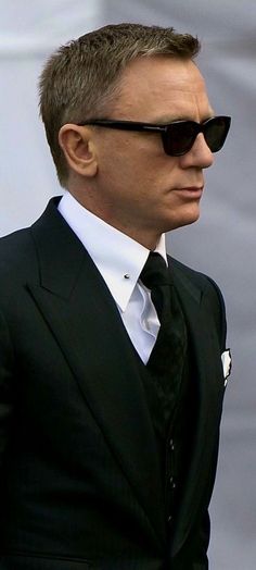 a man in a suit and sunglasses looks off into the distance