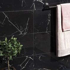 a bathroom with black marble walls and white towels hanging on the towel rack next to a potted plant