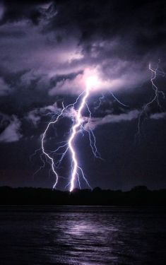 lightning striking over the ocean at night time