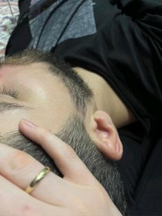 a close up of a person with a ring on his finger touching another persons head