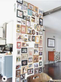 there is a wall with many pictures on it in the living room and kitchen area