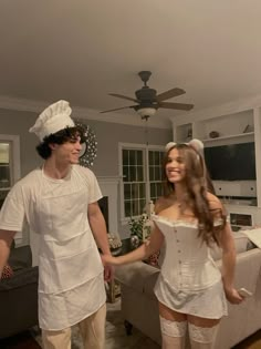 a man and woman are dressed up in white outfits while walking through a living room