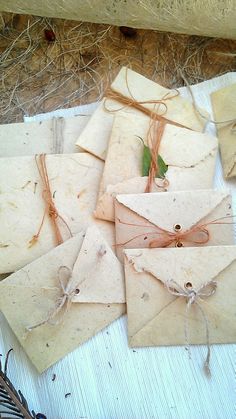 several envelopes tied with twine and string on top of a table next to feathers