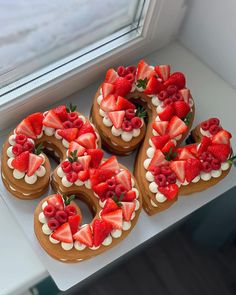 some heart shaped cookies with strawberries and cream on them are sitting in front of a window