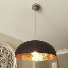 a black and gold lamp hanging from the ceiling in a room with a mirror on the wall