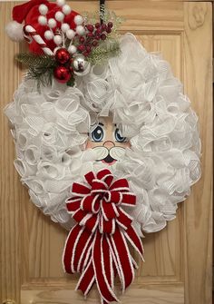 a door hanger with a santa clause's face and red bow on it