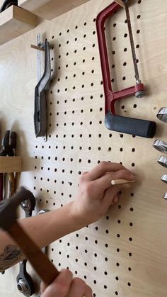 a person is working on a pegboard with tools attached to the pegs and hooks