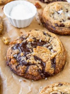 chocolate chip cookies on parchment paper next to a cup of cream and some other items