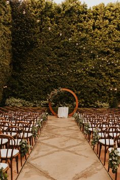 an outdoor ceremony with rows of chairs set up in front of trees and greenery