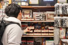 a man is looking at items on display in a store with shelves full of toys