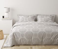 a bed with white and grey bedspread in a bedroom next to a basket