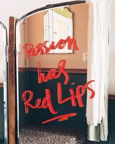 a mirror with red writing on it in a room next to a door and window