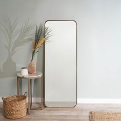 a mirror sitting on top of a wooden floor next to a table with a potted plant