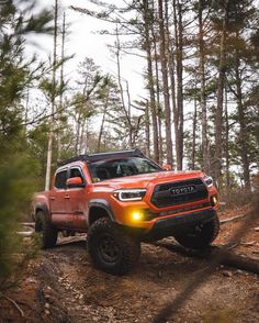 an orange toyota truck driving through the woods