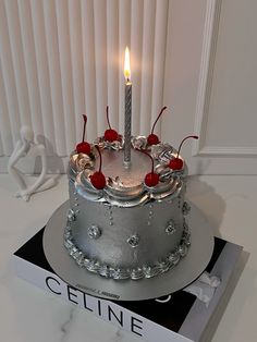 a cake with a lit candle on top of it sitting next to a copy of the book celine