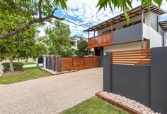 a modern house with wood and metal accents on the front yard, fenced in area next to it