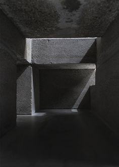 an empty concrete tunnel with light coming in from the end and shadows on the floor