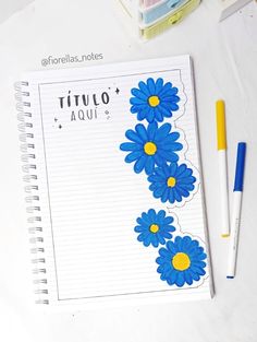 a notepad with blue flowers on it next to a pen