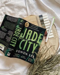 an open book sitting on top of a wooden plate next to a plant and a toothbrush