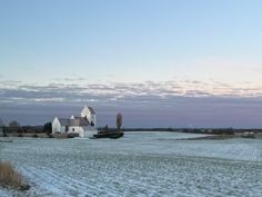 a large white house sitting on top of a snow covered field next to a farm