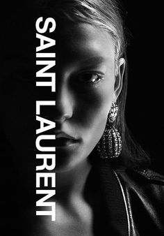 a black and white photo of a woman with earrings on her head, in front of a dark background