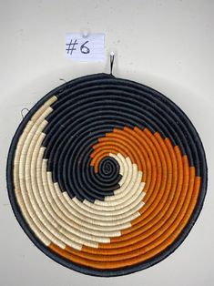 an orange, white and black circular basket hanging on a wall with a price tag